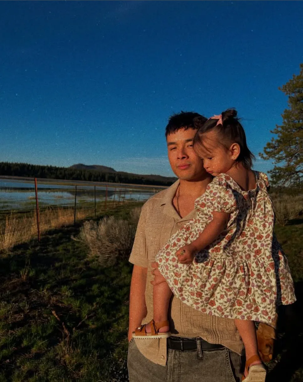 Steve Vo, founder of Rise Local, holding his daughter at dusk in the Oregon mountains